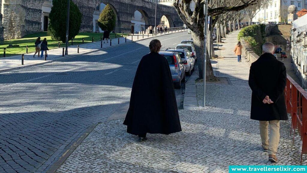 Caped student walking around at the University of Coimbra.